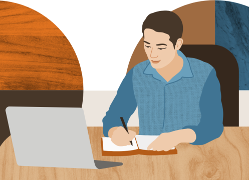 Man sitting at a computer, holding a pen and ready to write in a notebook